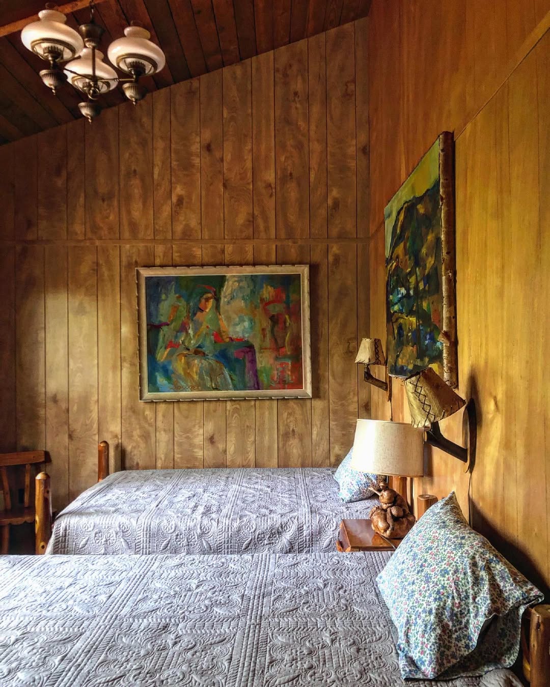 Cozy bedroom with artwork and wood paneling in Main Lodge