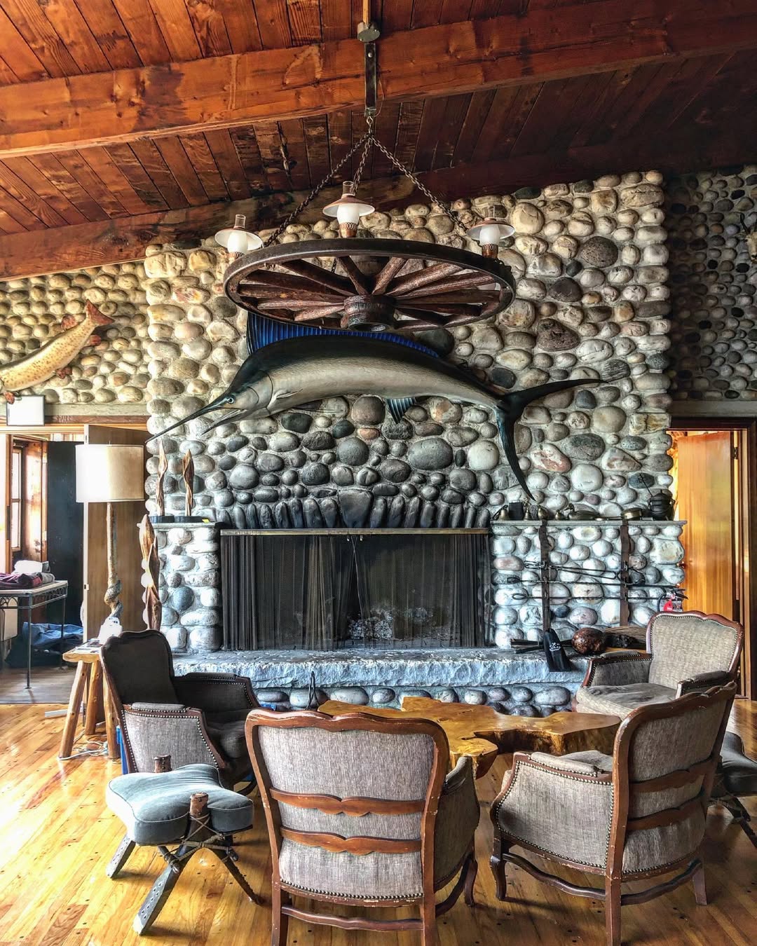 Stone fireplace with river rocks and wagon wheel chandelier in Main Lodge